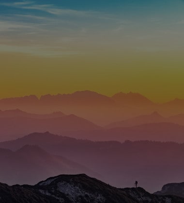 Man walking on mountain range at sunrise